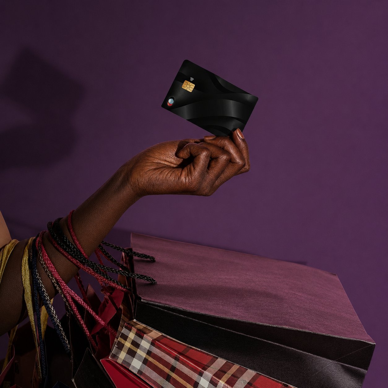 A hand holding a Blink card above a stack of designer shopping bags